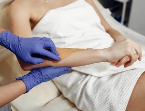 Knik Fairview Alaska esthetician applying wax treatment to remove hair from woman's arm